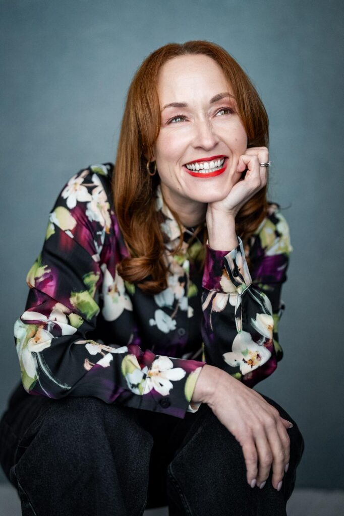 Headshot of Sara Lawson, smiling, chin resting on her hand.