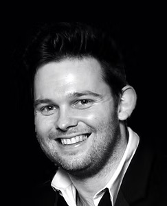 Headshot of Jon Stacey, smiling, in black and white.