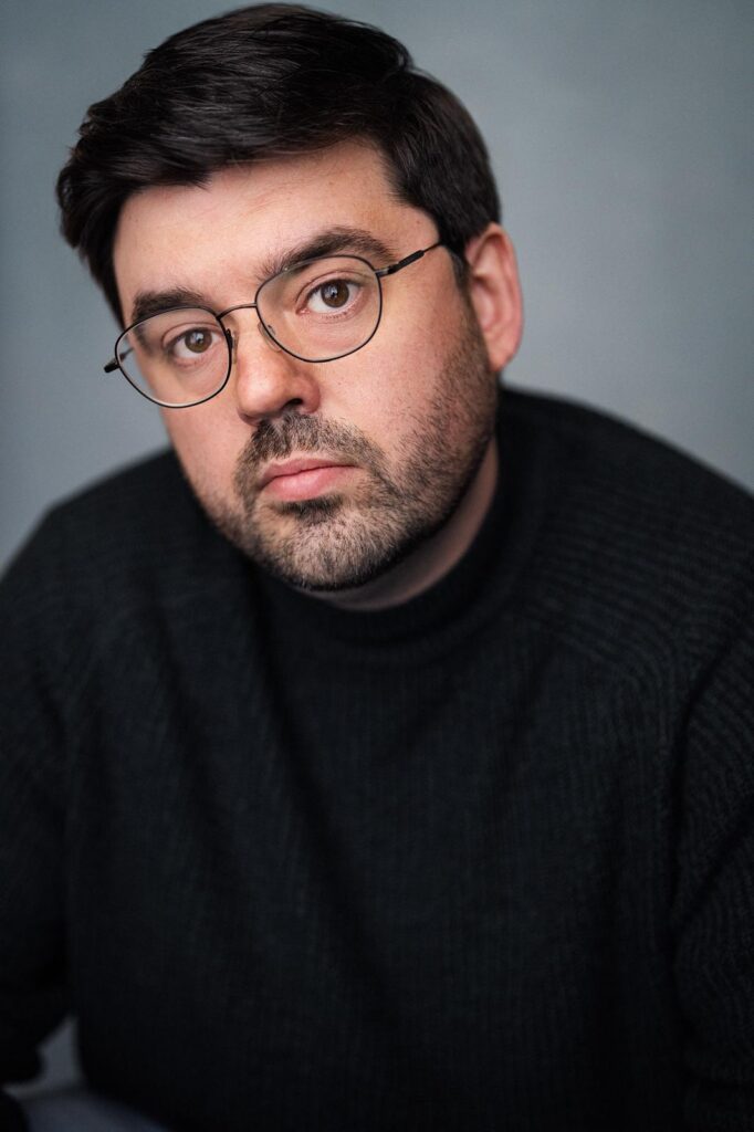 Headshot of Dan Cowtan, in glasses and a dark jumper.