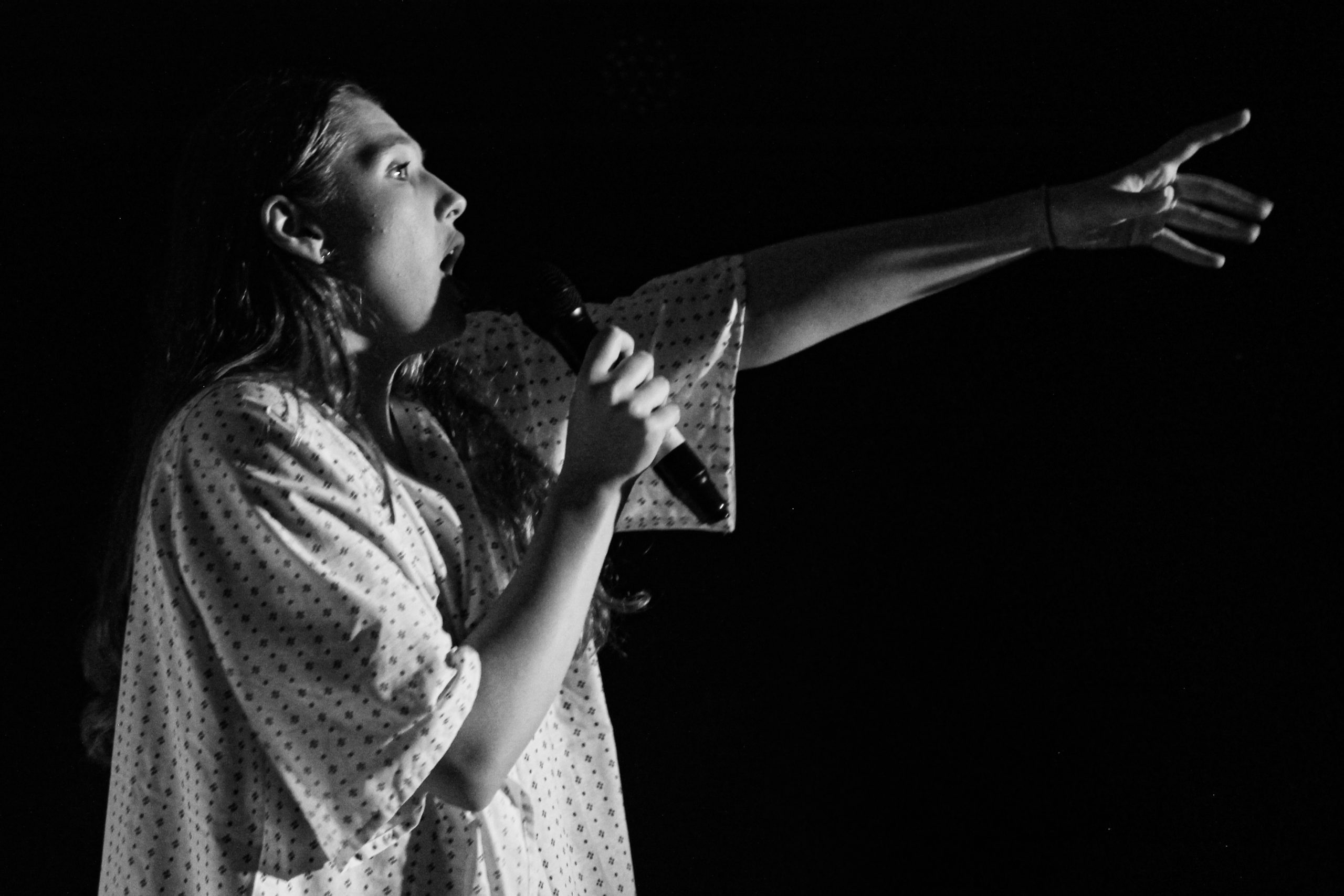 Black-and-white photo of a singer in a patterned shirt reaching out with one arm.